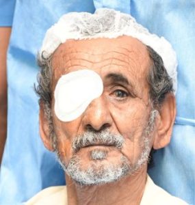Close-up of an elderly patient with an eye bandage, resting after eye surgery.